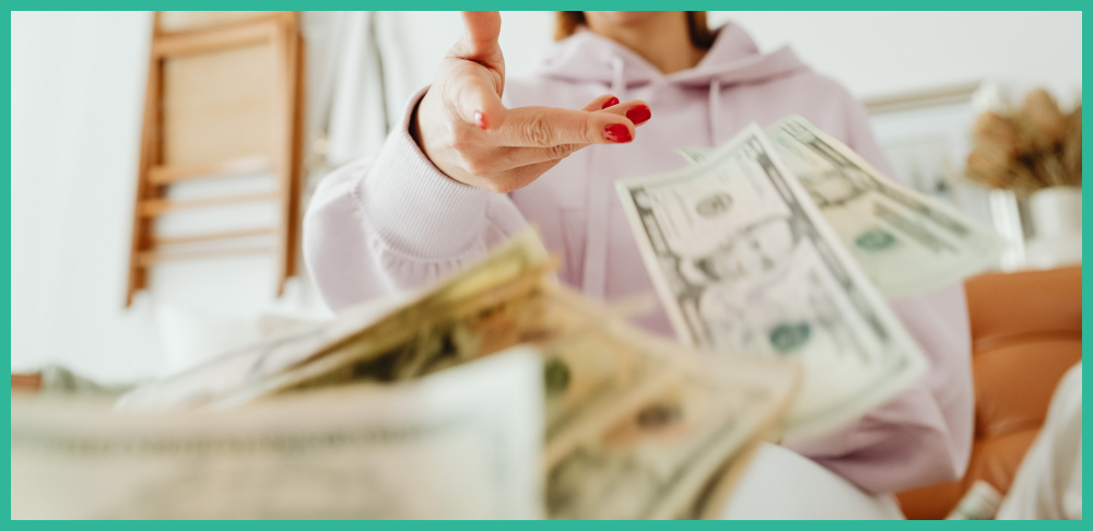 Woman in a pink hoodie throwing American money
